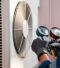 Technician inspecting HVAC system with gauges next to air conditioning unit, highlighting HVAC repair services.